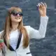 smiling very stylish young woman in white business suit long blond ha holding two dice in one hand and casino chips in the other