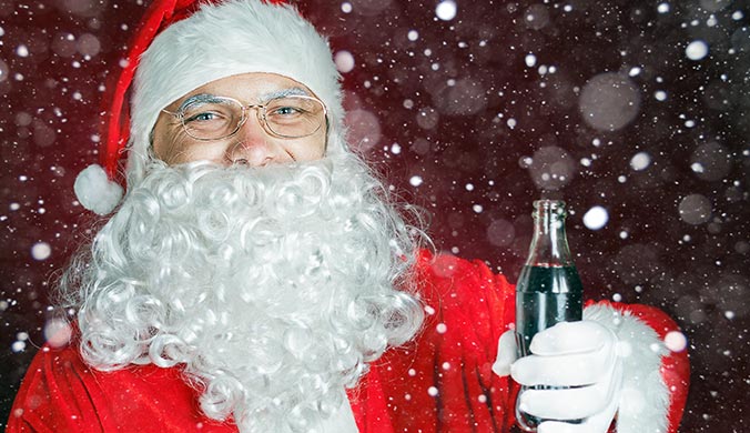 An image of a man dressed as Santa holding a dark beverage in a glass bottle surrounded by snowflakes - Everygame Red