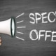 A man holding a loudspeaker against a blackboard with the text special offer written in white chalk no deposit bonus deals