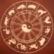 A round wheel featuring the Chinese Zodiac symbols with a yin yang symbol in the middle on a dark red wooden surface