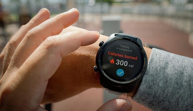 A photo of a person wearing a smart watch showing calories burned on a blurred background