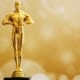 A golden Oscar statue against a blurry sparkly golden background