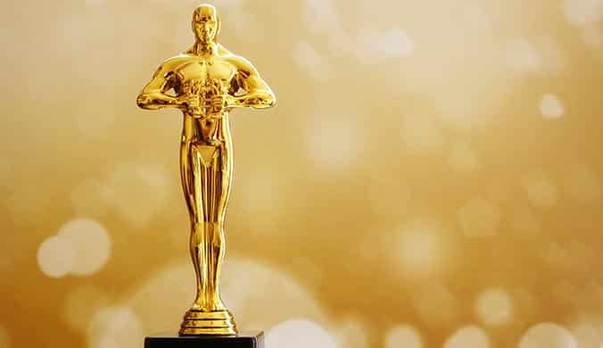 A golden Oscar statue against a blurry sparkly golden background
