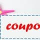 A photo of pair of pink scissors cutting the blue perforated edge of white coupon featuring the word coupon in red