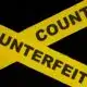 An image of two strips of yellow tape the police use to cordone off a space with Counterfeit written on it