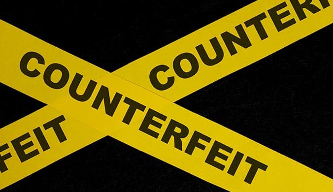 An image of two strips of yellow tape the police use to cordone off a space with Counterfeit written on it