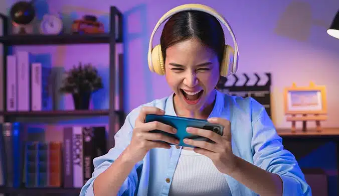 young woman playing an online game on her phone with a headset on